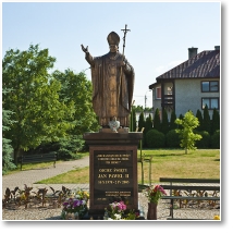 (14/72): Ostroka - koci Farny pw. NMP i w. Mikoaja, pomnik papiea JPII